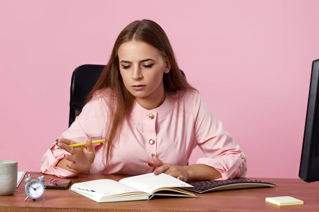 kaunis naispuolinen johtaja, joka käyttää PC-tietokonetta online-työhön vaaleanpunaisella taustalla - Valokuva, kuva
