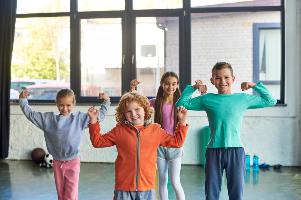 vier mooie kleine kinderen in sportkleding spelen spieren en glimlachen op de camera, kind sport - Foto, afbeelding