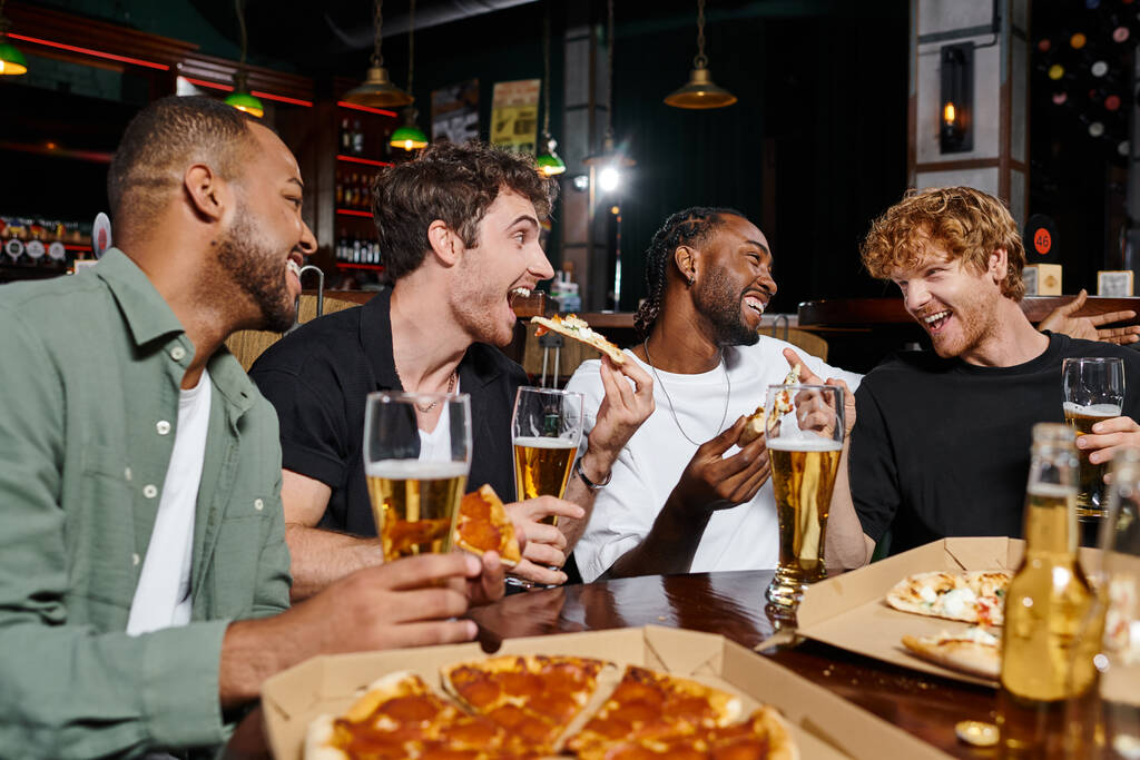 4人の幸せな異人種間の友人のグループ ピザを食べ,バーでビールを飲む,独身パーティーの男性 - 写真・画像