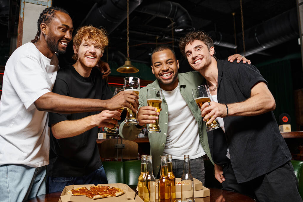feliz interracial homens brindar com copos de cerveja no bar durante despedida de solteiro, amizade masculina - Foto, Imagem