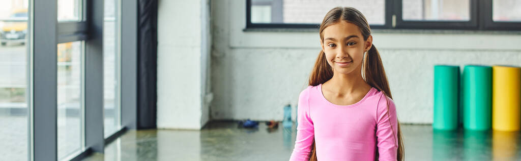 весёлая девочка-подросток с длинными волосами в спортивной одежде, улыбающаяся в камеру, детский спорт, баннер - Фото, изображение