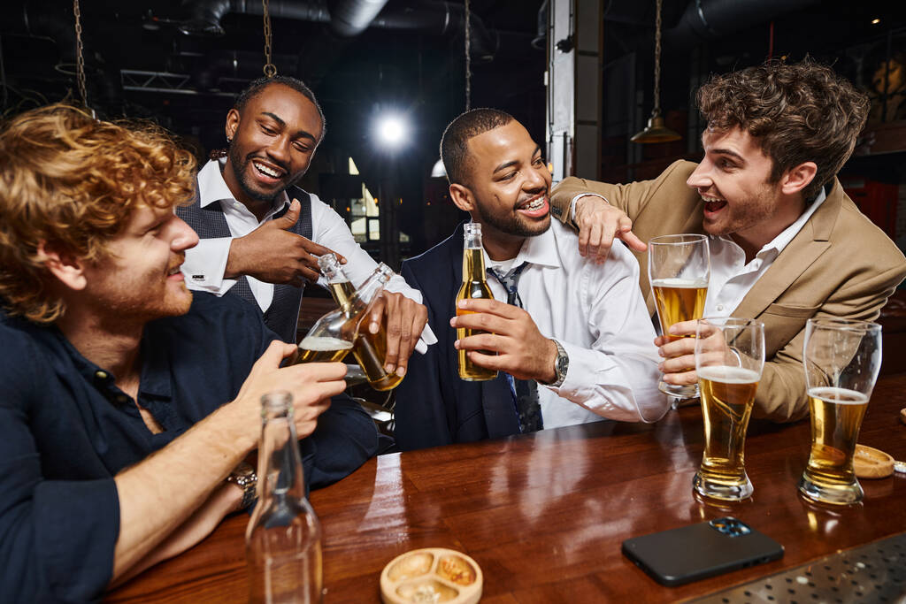 バーでビールを試飲するために正式に身に着けている陽気な異人種間の同僚,仕事の後に楽しんでいる男性 - 写真・画像
