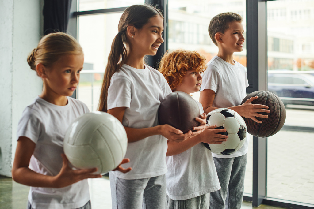four cute preadolescent children with different kinds of balls posing in profile, child sport - Photo, Image