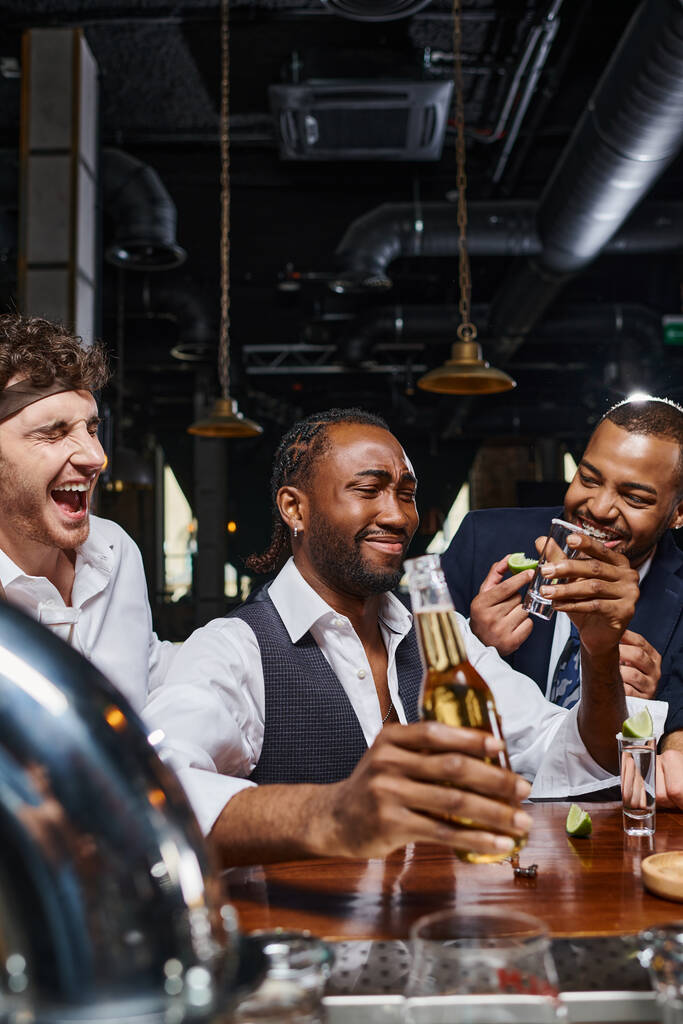 feliz e bêbado interracial amigos bebendo tequila e cerveja no bar após o trabalho, amizade masculina - Foto, Imagem