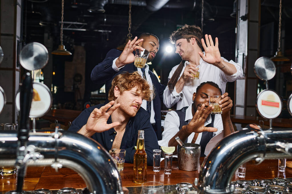 quatro amigos multiculturais bêbados cobrindo rostos de luz brilhante, tiros de tequila, cerveja e uísque - Foto, Imagem