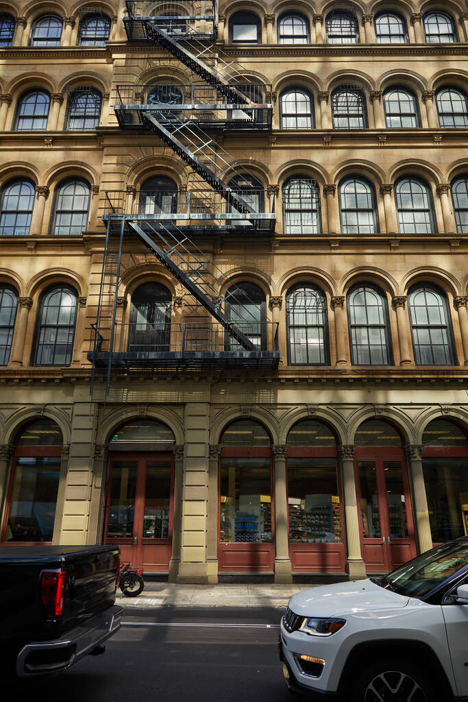voitures se déplaçant sur la chaussée le long d'un bâtiment vintage avec escalier d'évacuation à New York, vue sur la rue - Photo, image