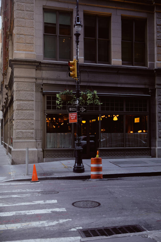 street pole with flowerpots and traffic lights near building with restaurant in new york city - Photo, Image