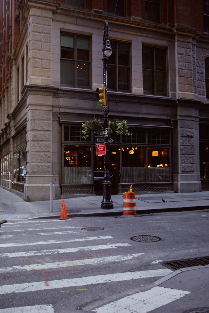 Straßenmast mit Ampeln und Blumentöpfen in der Nähe eines Gebäudes mit Restaurant in New York City - Foto, Bild