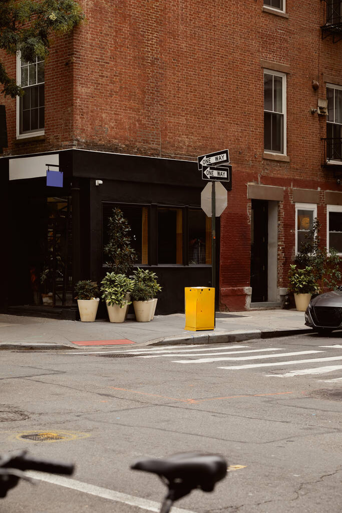 кирпичное здание с витриной и цветочными горшками рядом с перекрестком в центре Нью-Йорка, городской шарм - Фото, изображение