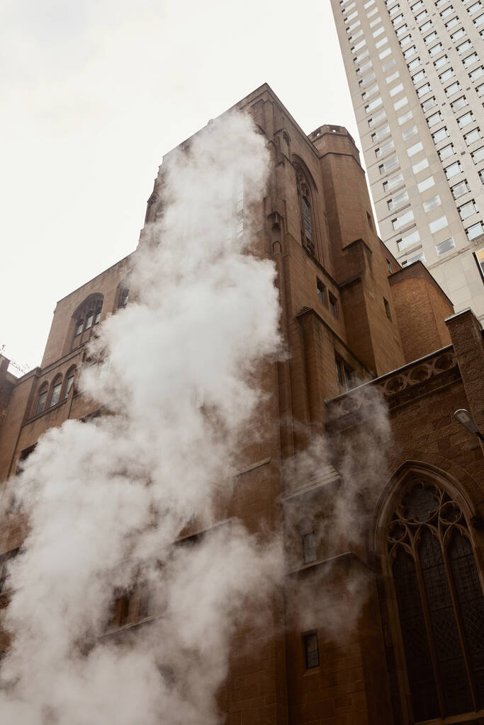 пар возле католической церкви из красного кирпича и небоскреба на городской улице города Нью-Йорка, вид с низкого угла - Фото, изображение