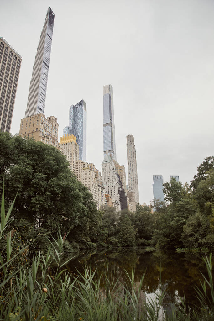 γραφική θέα των δέντρων και της λίμνης κατά των σύγχρονων ουρανοξύστες στη Νέα Υόρκη, φθινοπωρινή σκηνή μητρόπολη - Φωτογραφία, εικόνα
