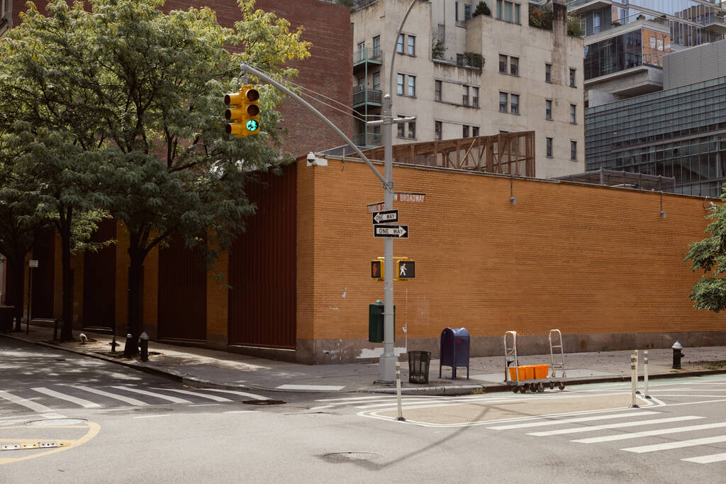 道路の棒の近くのレンガの塀は,ニューヨークの都市で歩行者を横断するクロスロードのトラフィックライトと - 写真・画像