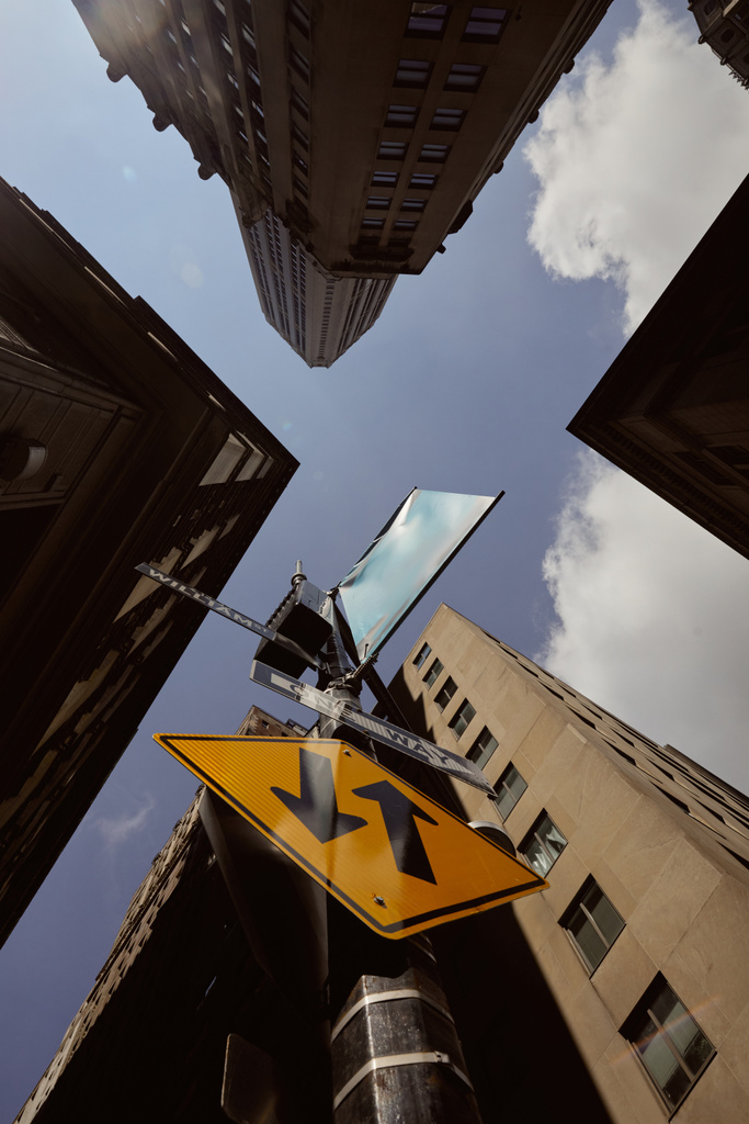 ニューヨーク市の青空に対する高い建物の近くの交通標識を持つストリートポールの下部ビュー - 写真・画像
