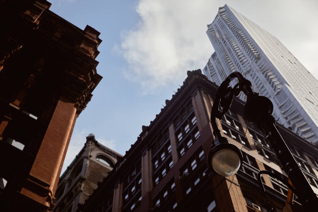 nízký úhel pohledu na lucernu v blízkosti moderních a historických budov proti modré oblačné obloze v New Yorku - Fotografie, Obrázek