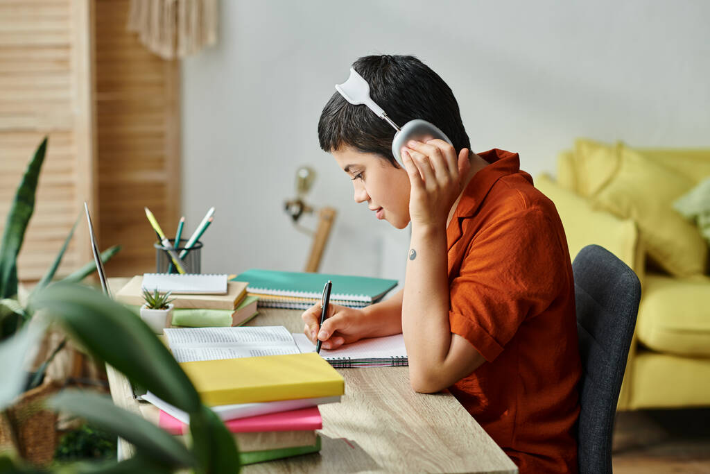 gerichte vrolijke student met koptelefoon aan het bureau voor laptop tijdens online les, onderwijs - Foto, afbeelding