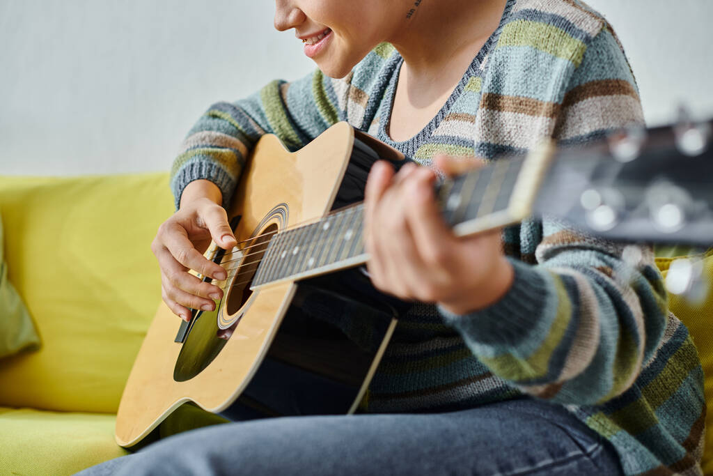 ostříhaný pohled mladé ženy s piercing a tetování učení, jak hrát na kytaru, vzdálená třída - Fotografie, Obrázek