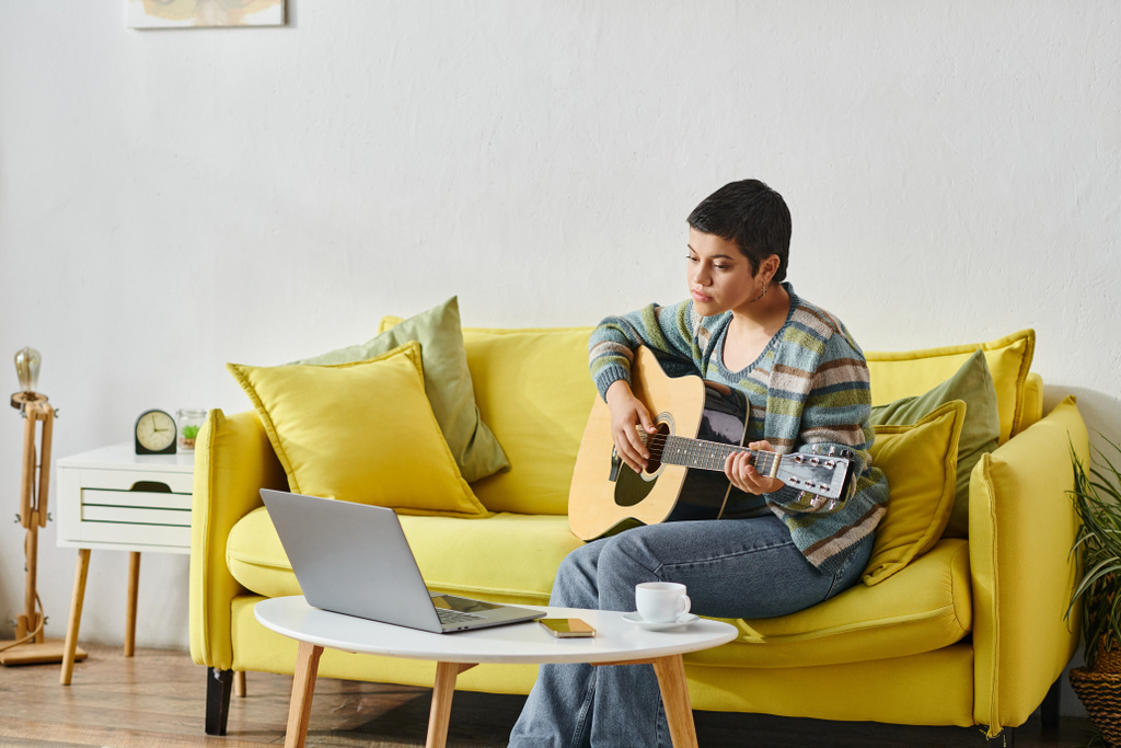привлекательная женщина в повседневной одежде учится играть на гитаре на удаленном уроке музыки - Фото, изображение