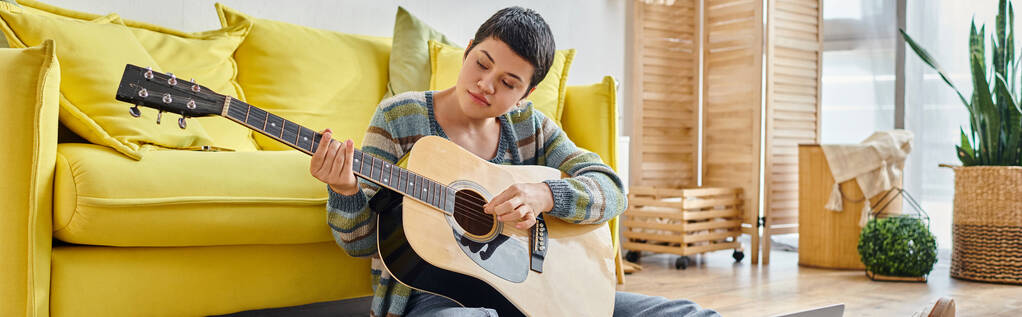 geconcentreerde jonge vrouw met gitaar zittend op de vloer bij online muziekles, onderwijs thuis, banner - Foto, afbeelding