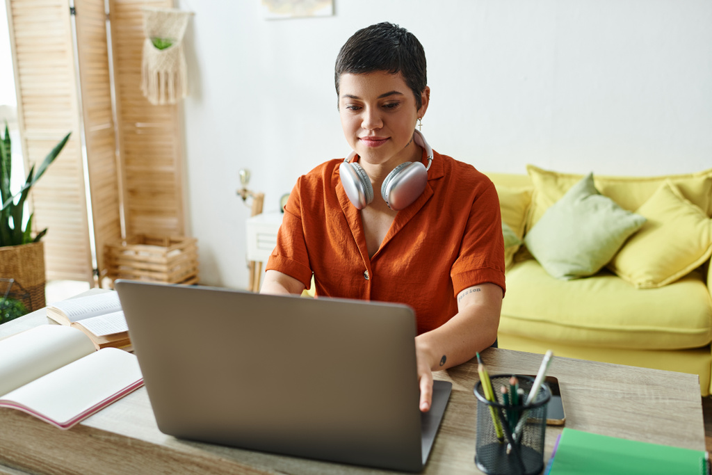 attraktive junge Frau im roten Hemd mit Kopfhörern, die hart am Laptop lernt, Bildung zu Hause - Foto, Bild
