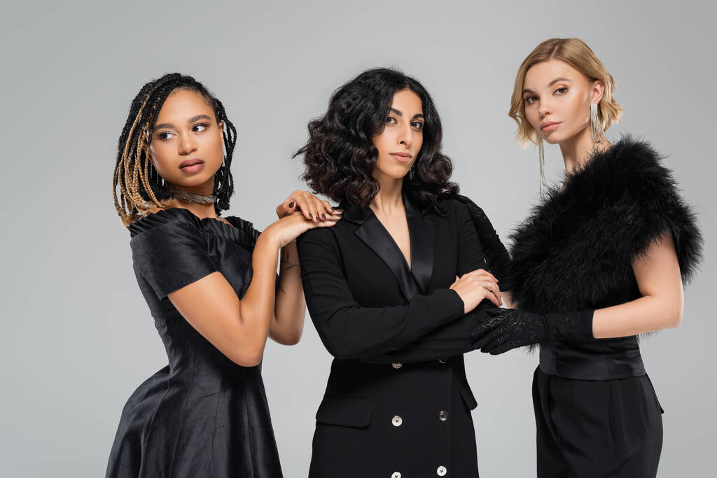 tři okouzlující multikulturní přítelkyně v černém elegantním oblečení na šedé, rozmanité kráse - Fotografie, Obrázek