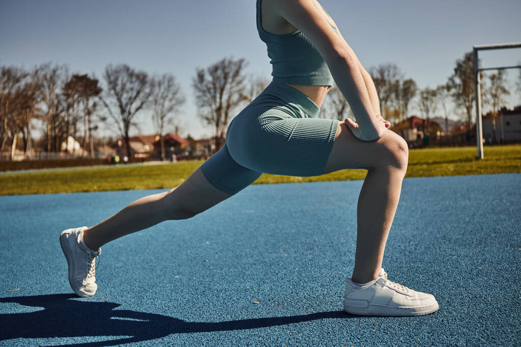 cropped view of sportswoman with ponytail exercising in activewear outdoors, woman doing lunges - Photo, Image