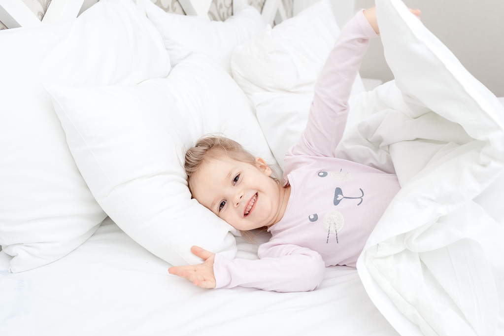κοριτσάκι παιδί σε μαλακό κρεβάτι - Φωτογραφία, εικόνα
