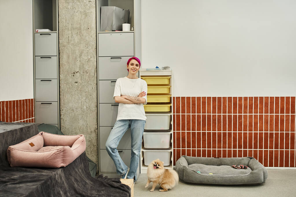 Hundesitterin steht in voller Länge neben verspielter Pommernspitze in komfortablem Haustierhotel - Foto, Bild