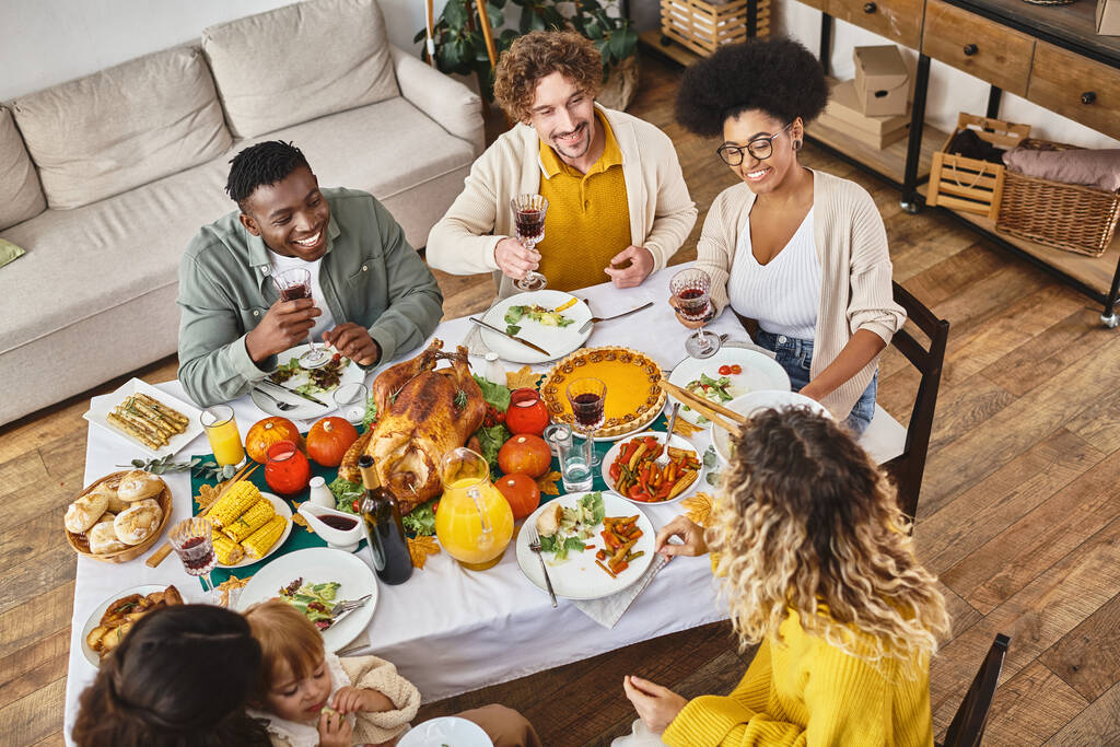 Gelukkige Thanksgiving, vreugdevolle interraciale vrienden en familie bijeenkomst aan feestelijke tafel met kalkoen - Foto, afbeelding