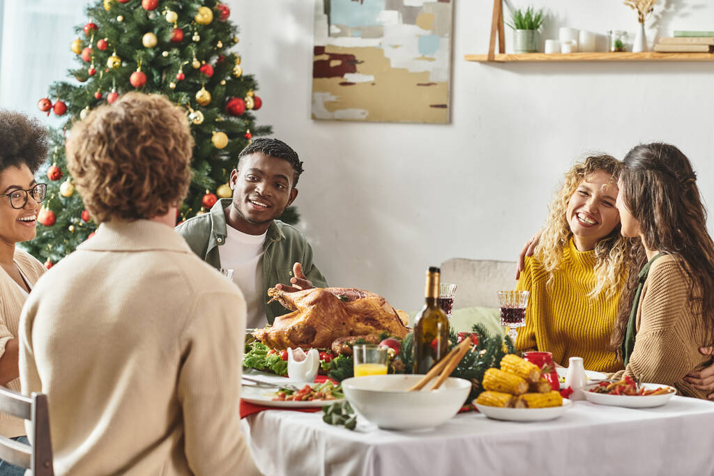 молодая многонациональная семья празднует Рождество вместе за праздничным столом с индейкой и вином - Фото, изображение