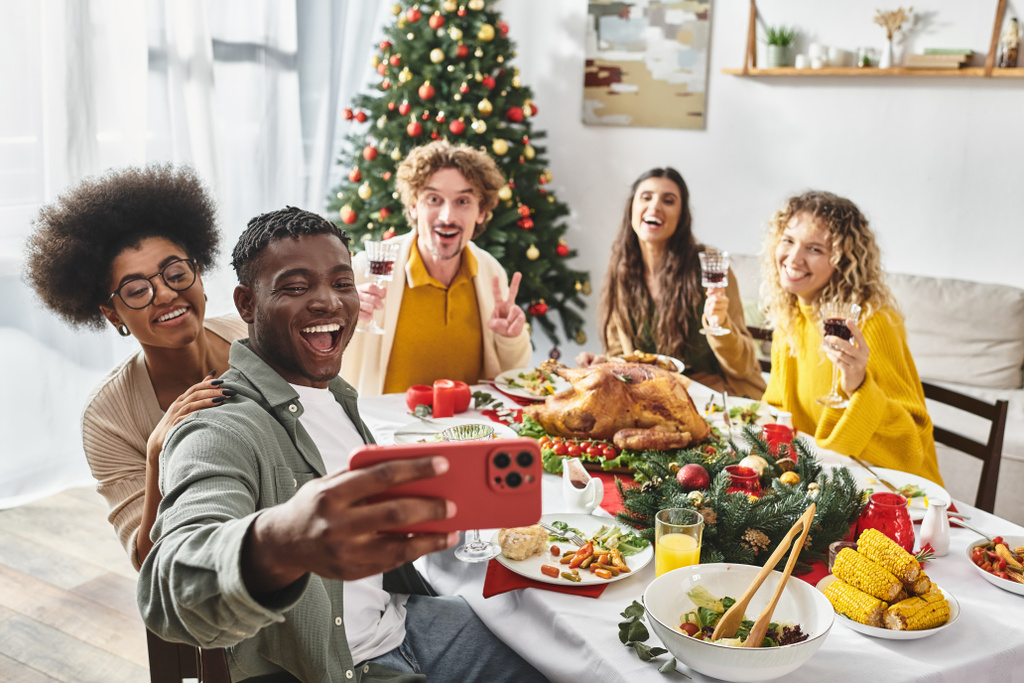 χαρούμενα πολυπολιτισμικούς συγγενείς λαμβάνοντας selfies πόσιμο κρασί και gesturing ενεργά, Χριστούγεννα - Φωτογραφία, εικόνα