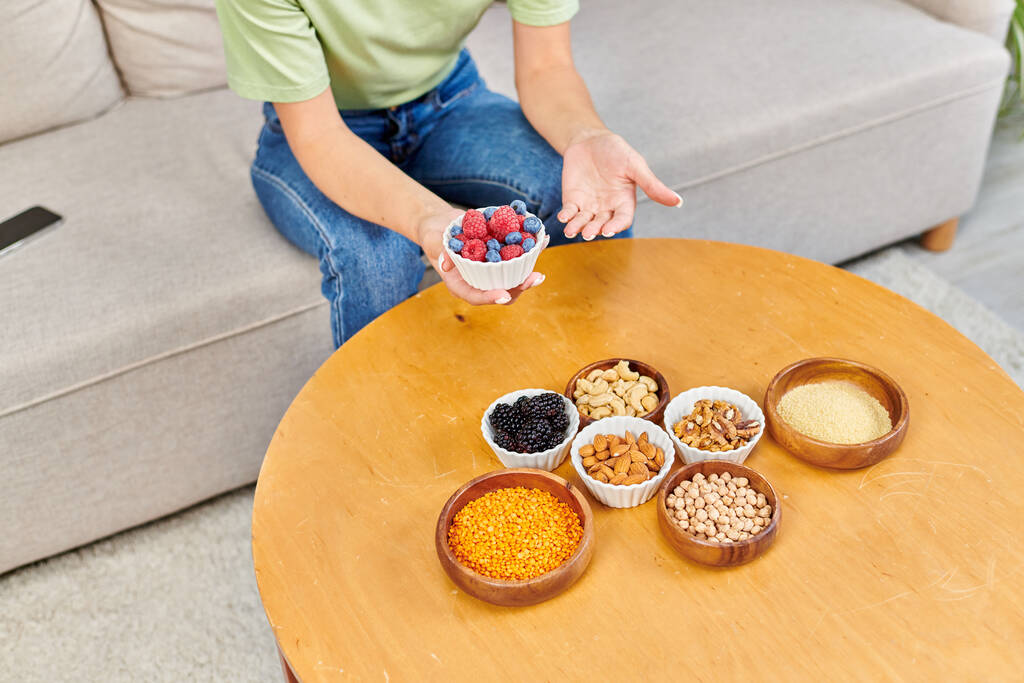 vue de dessus de la femme avec des mûres fraîches près de l'assortiment de produits à base de plantes sur la table à la maison - Photo, image