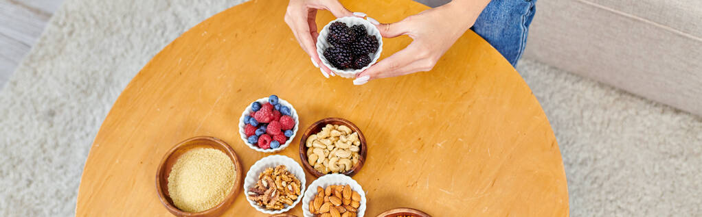 top view of woman with fresh blackberries near various plant-based products on table at home, banner - Photo, Image