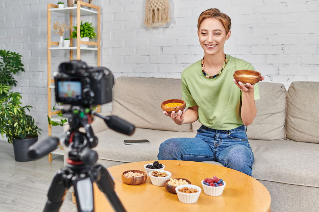 tevreden vrouw met couscous en linzen in de buurt van set van vegetarisch voedsel en wazig digitale camera - Foto, afbeelding