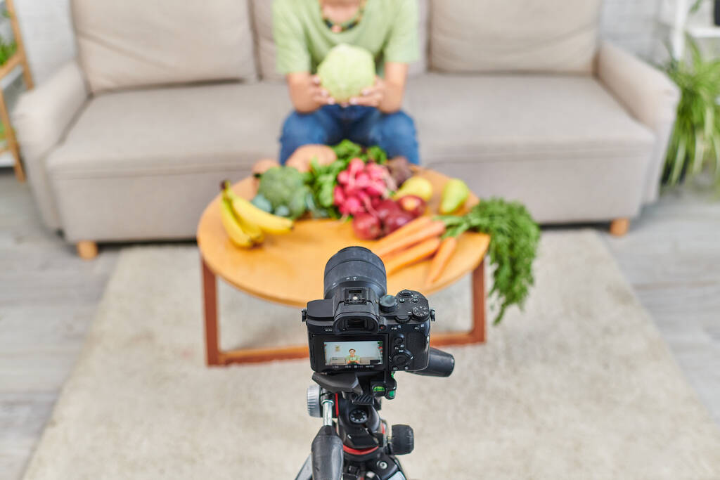 visão de alto ângulo da câmera digital perto de mulher cortada com produtos de origem vegetal durante blog de vídeo - Foto, Imagem
