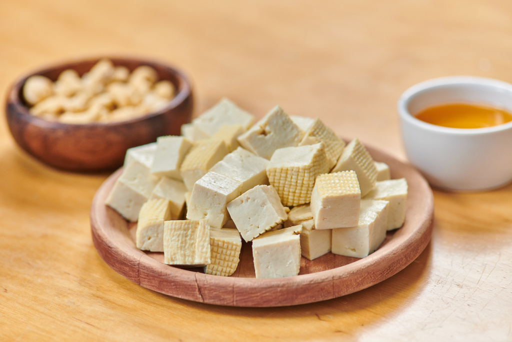 lähikuva kuutioidusta tofu-juustosta lähellä cashew-pähkinöitä ja oliiviöljyä pöydällä, kasvipohjainen keittiö - Valokuva, kuva