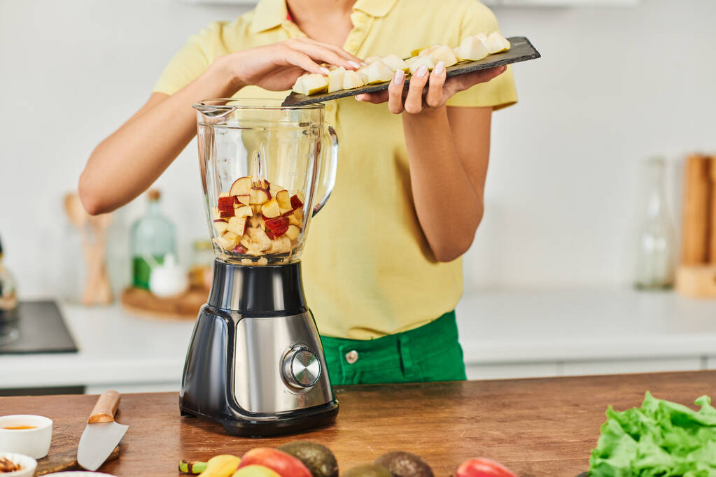 cropped view of woman adding chopped fruits in electric blender, healthy vegetarian home cooking - Photo, Image