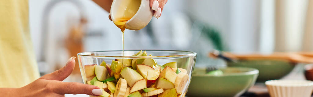 обрезанный вид на вегетарианку, наливающую мед в стеклянную миску с вкусным фруктовым салатом, баннером - Фото, изображение