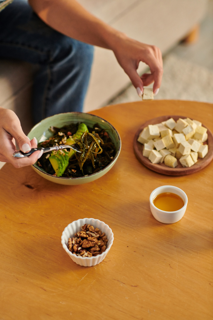 обрізана жінка біля вегетаріанського салату на рослинній основі і сиру тофу з оливковою олією і волоськими горіхами на столі - Фото, зображення