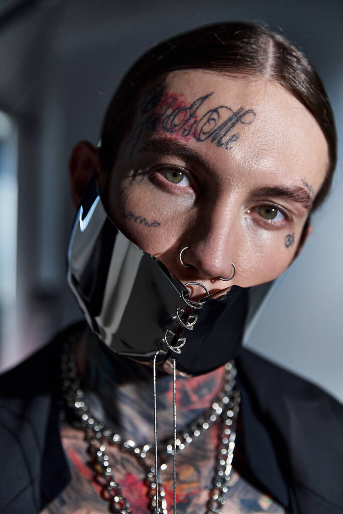 カメラ,ファッションコンセプトを見る未来的なマスクでタトゥーを持つ若いスタイリッシュな男の肖像画 - 写真・画像