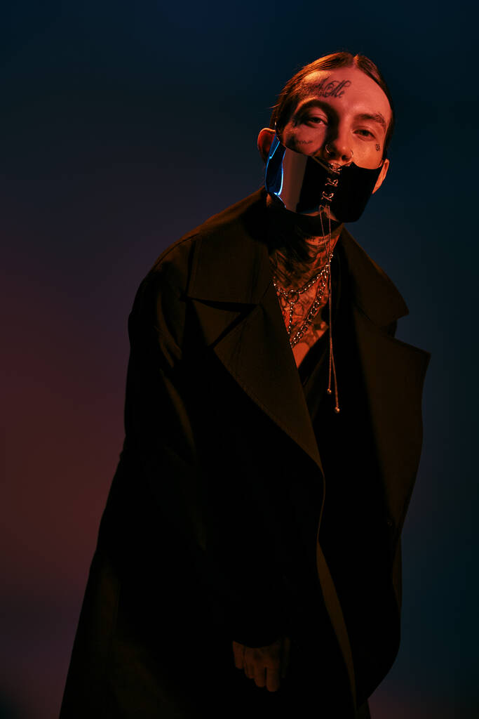 vertikální záběr dobře vypadajícího mladého muže ve stylovém dystopickém oblečení s tkanou maskou, módní - Fotografie, Obrázek