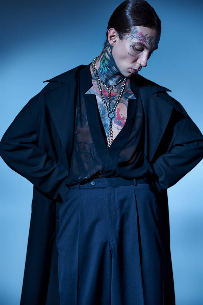 függőleges lövés fiatal elegáns férfi fekete ruhába tetovált pózol kezét csípő, divat - Fotó, kép