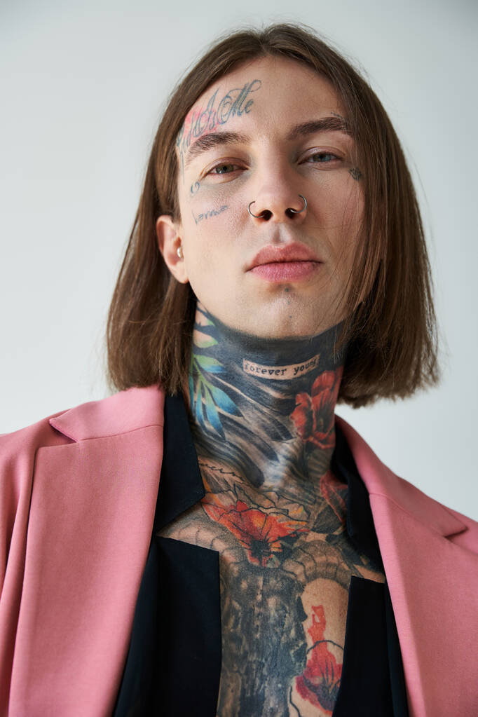 вертикальный снимок молодой стильной мужской модели с татуировками и пронзительным взглядом на камеру, моду - Фото, изображение
