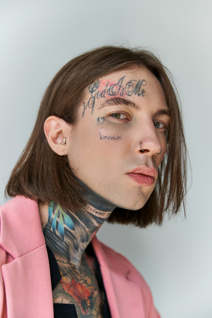 retrato de joven guapo con tatuajes elegantes en la cara mirando a la cámara, concepto de moda - Foto, imagen