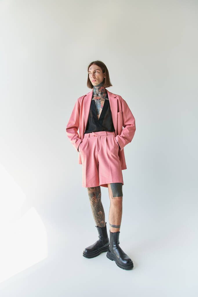 vertikale Aufnahme eines hübschen jungen Mannes in rosa Blazer und Shorts mit den Händen in den Taschen, Mode - Foto, Bild