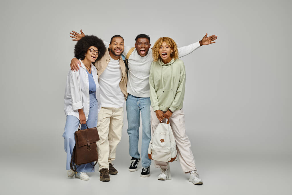 junge afrikanisch-amerikanische Freunde in Freizeitkleidung mit Rucksäcken, die fröhlich in die Kamera lächeln, Studenten - Foto, Bild