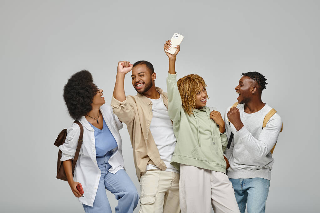 щасливі афроамериканські студенти веселяться і радісно посміхаються на сірому фоні, вивчаючи концепцію - Фото, зображення