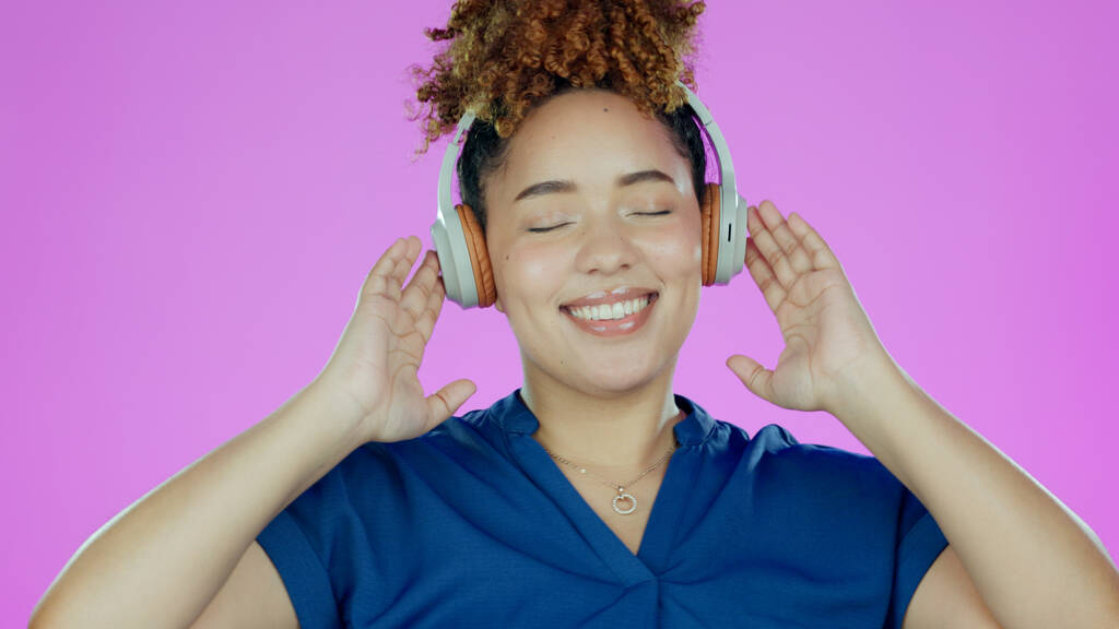 Słuchawki, szczęśliwy i kobieta z muzyką w studio słuchając piosenki, audio i radia. Taniec, szczęście i twarz osoby do streamingu subskrypcji, relaks i zabawa na fioletowym tle dla wellness. - Zdjęcie, obraz