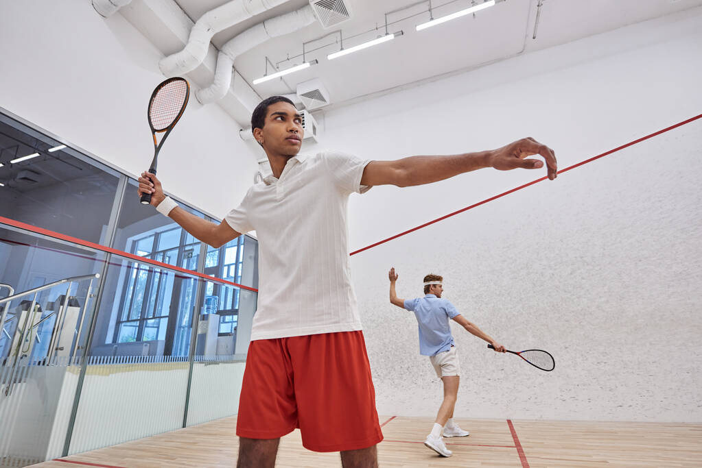 interracial players in sportswear playing squash together inside of court, active lifestyle - Photo, Image