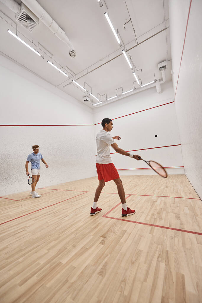 young interracial sportsmen playing squash together inside of indoor court, motivation and sport - Photo, Image