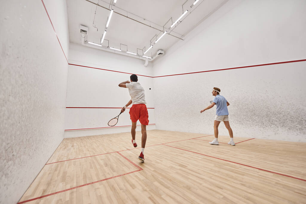 jugadores interraciales en ropa deportiva jugando squash juntos dentro de la cancha, fitness y motivación - Foto, Imagen